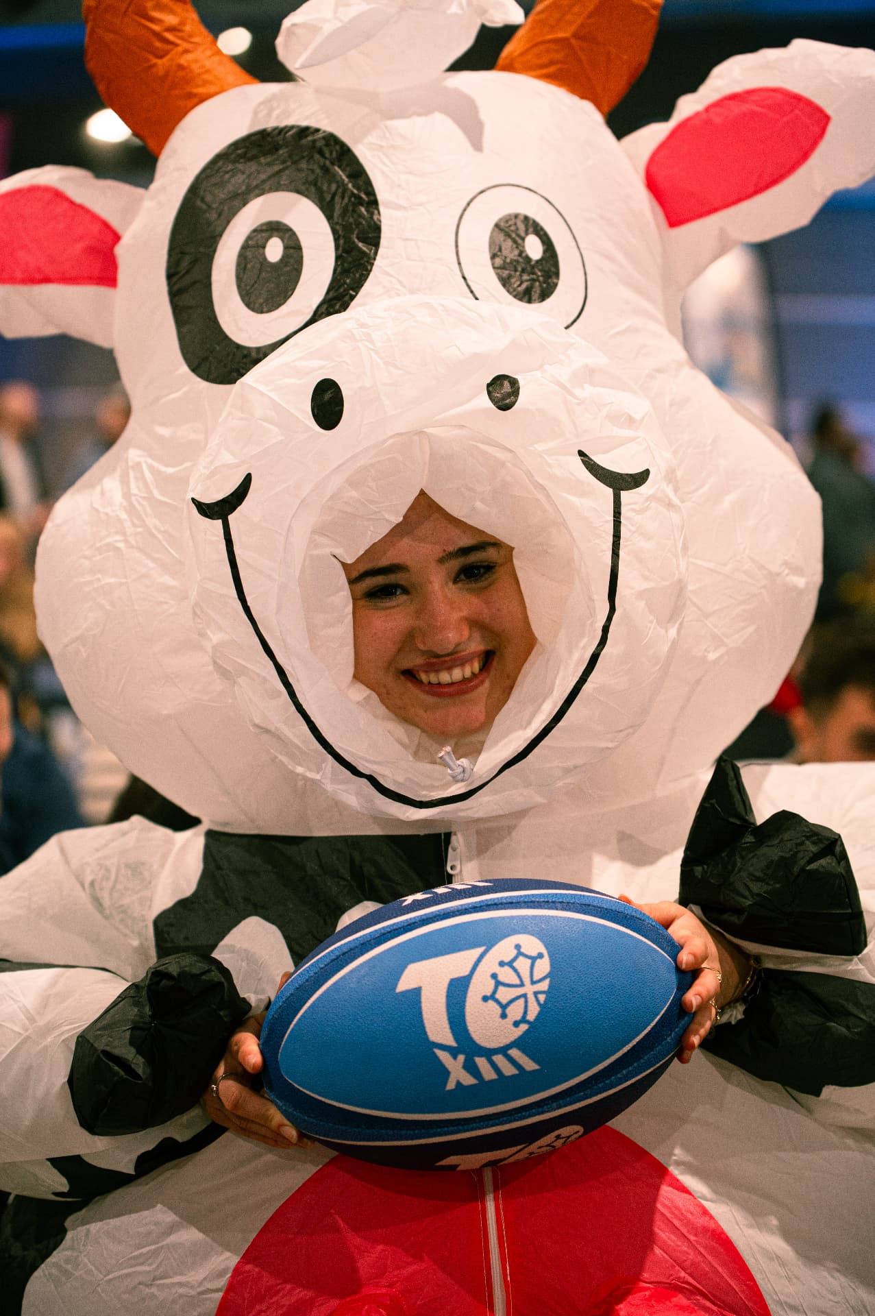 Supportrice en costume gonflable avec un ballon de rugby
